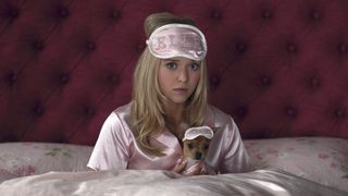 Lexi Minetree as Elle Woods in matching light pink pajamas with Bruiser sitting up in bed in Elle series