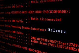 A close up image of red computer code on a black screen with the word malware displayed in white