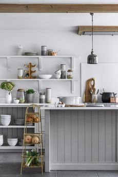 small kitchen island idea with grey panneling in a grey kitchen with white countertops and cooking utensils and accessories