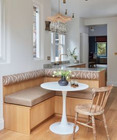 A small kitchen with a cozy dining nook featuring banquette seating and a small round table