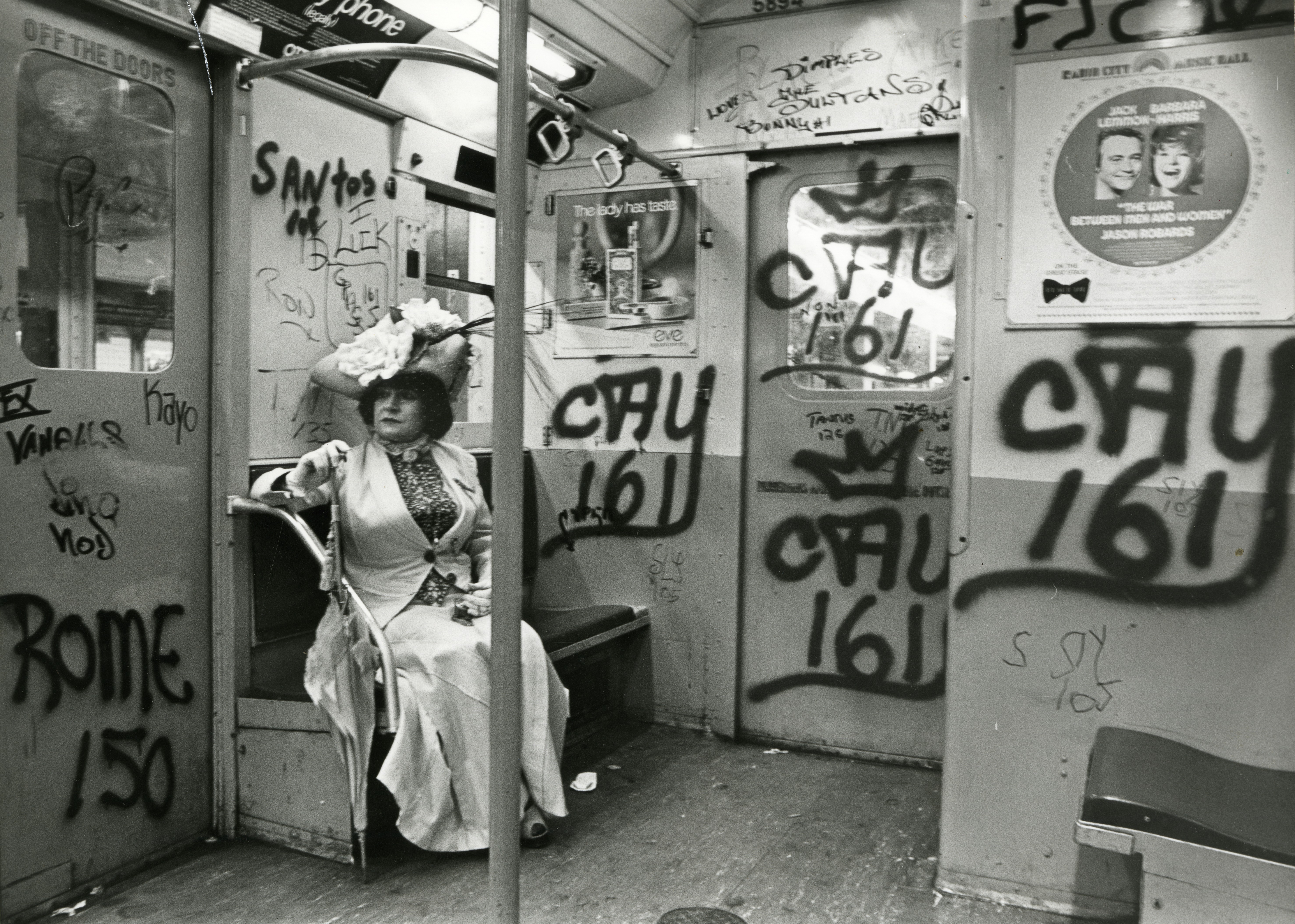 Editta Sherman in costume on a graffiti-strewn subway