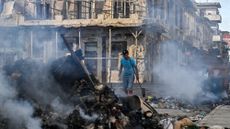 A man walking the streets of Cuba, with piles of rubbish set on fire