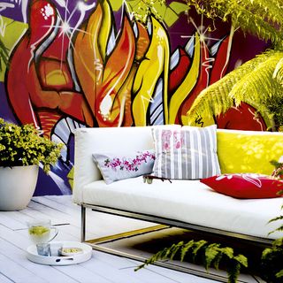 patio with graffiti wall art white sofa and stone paving