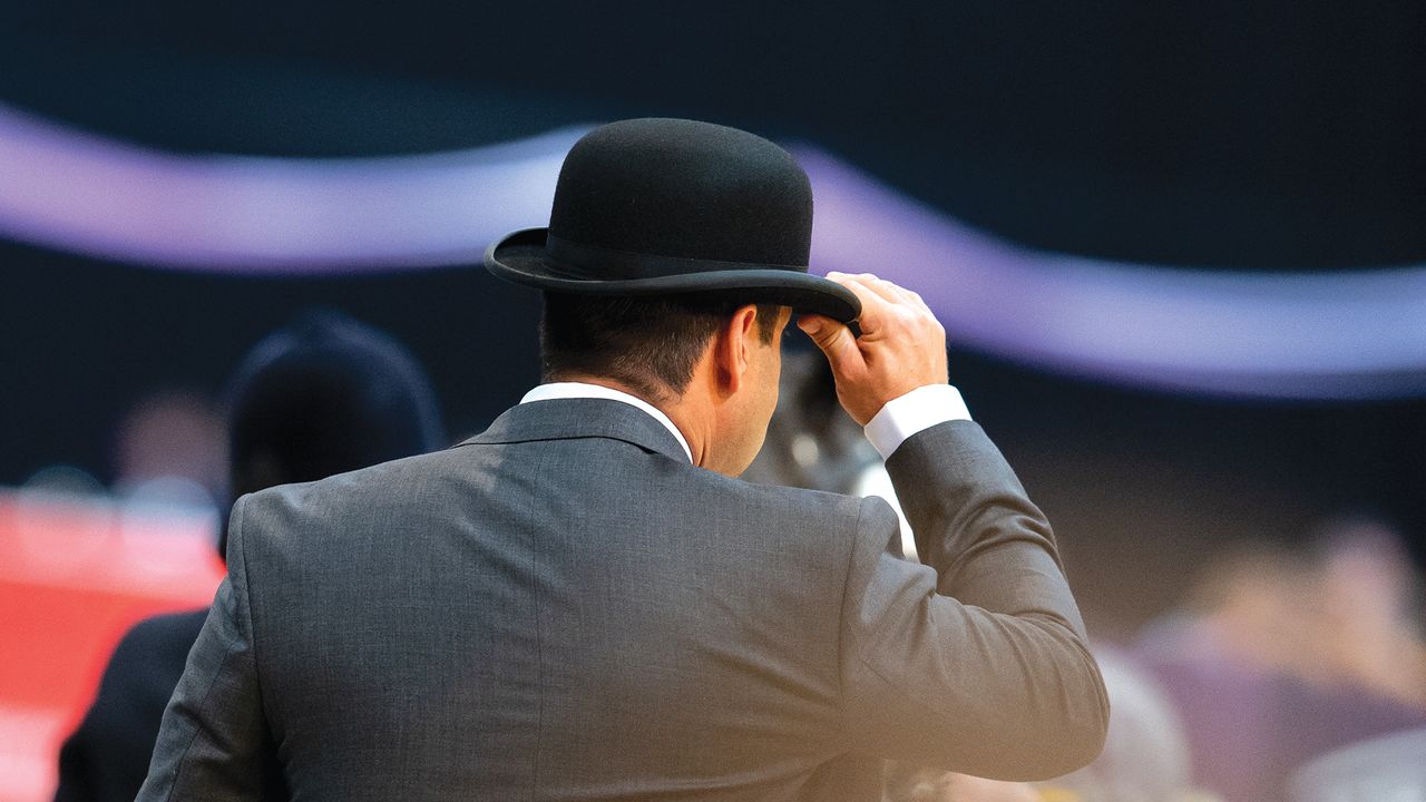 A male judge at HOYS wearing a suit and a bowler hat pictured from behind
