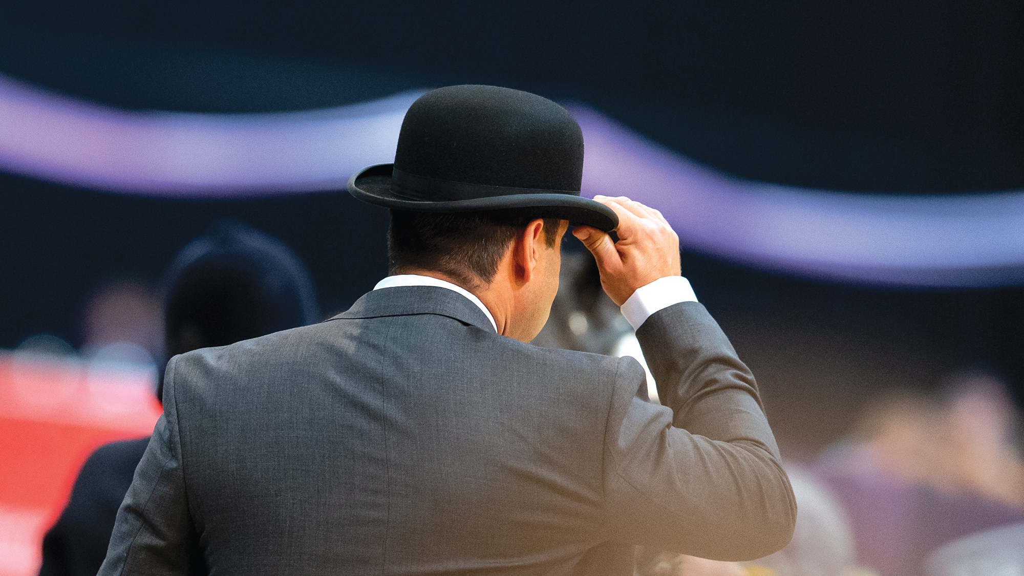 A male judge at HOYS wearing a suit and a bowler hat pictured from behind