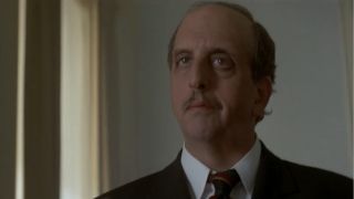 Vincent Schiavelli stands while smiling menacingly in Tomorrow Never Dies.