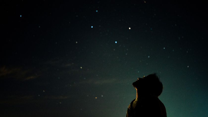 a man looks up at the night sky above.