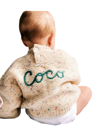 baby wearing a cream knitted jumper with coco embroidered on the back