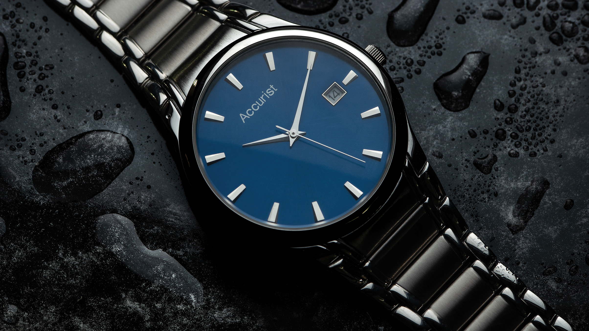 A close-up of an Accurist watch with a sleek blue dial, silver hour markers, and a stainless steel bracelet on a wet surface