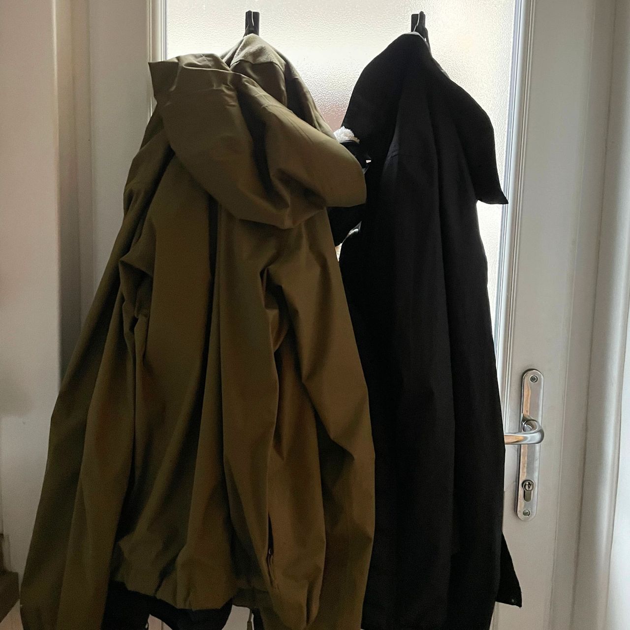 Black coat hooks with coats hanging off them