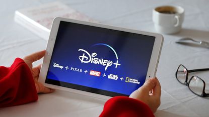 Disney + logo is displayed on the screen of a tablet 