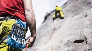 A climber belays his partner on a cliff