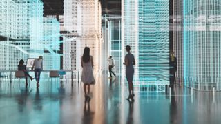Workers walking around a large warehouse with structures presented in holograms, denoting a digital workplace