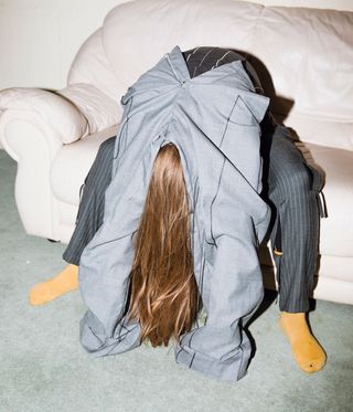 faceless model sitting down slouched over couch, wearing yellow socks and trousers on both arms and legs