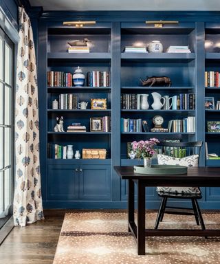 study room with dark blue cabinetry, wood floor with neutral rug, black desk and chair