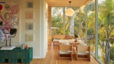 A cozy living nook with a wooden coffee table, an overhead pendant light, and a wall nearby with a large framed art piece, a mini row of paintings and a green tiled sideboard