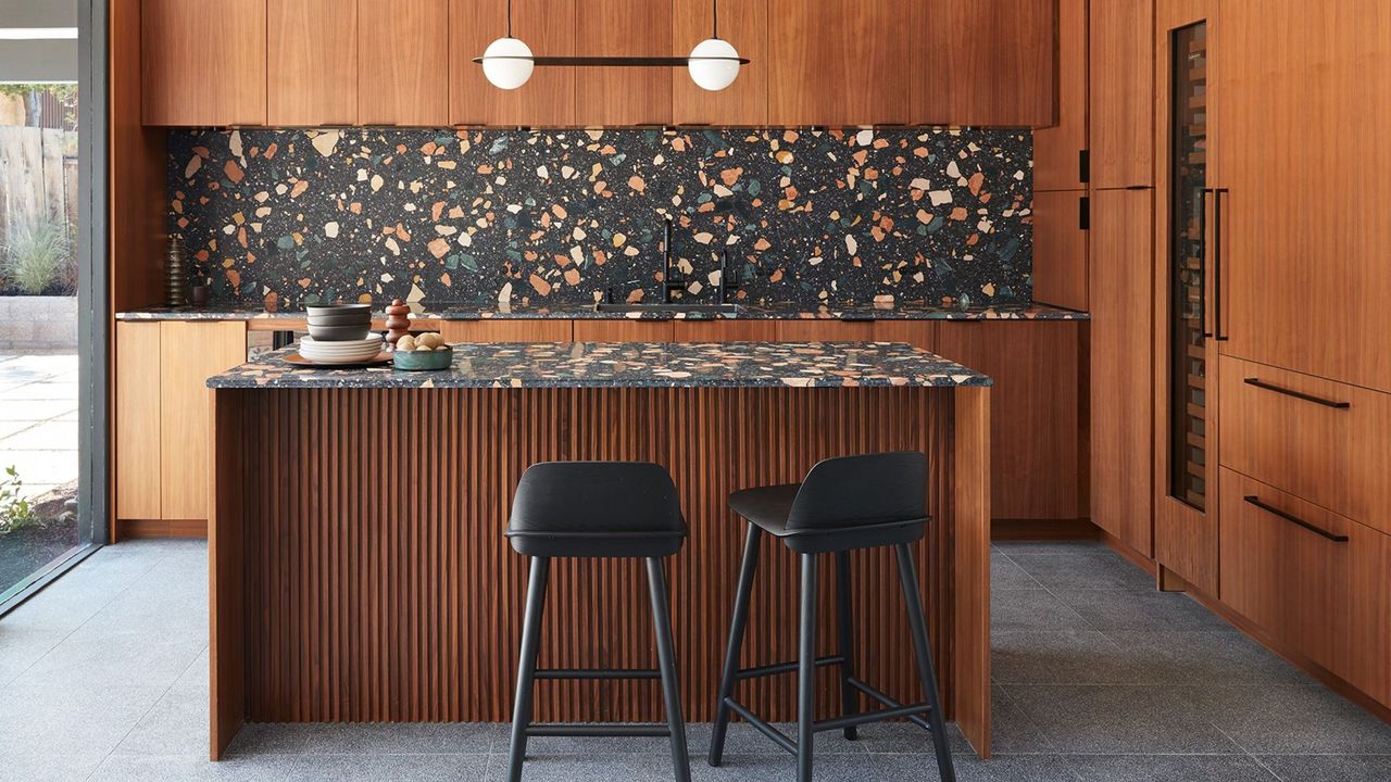 timber kitchen with terrazzo backsplash, fluted island bench, and black bar stools