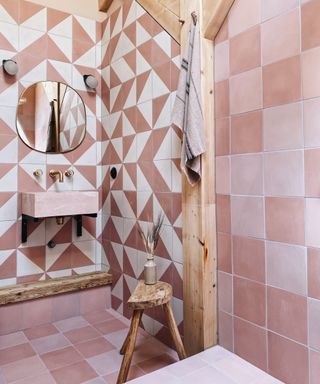 A shower room with pink and white triangular patterned tiles and a pink marble sink