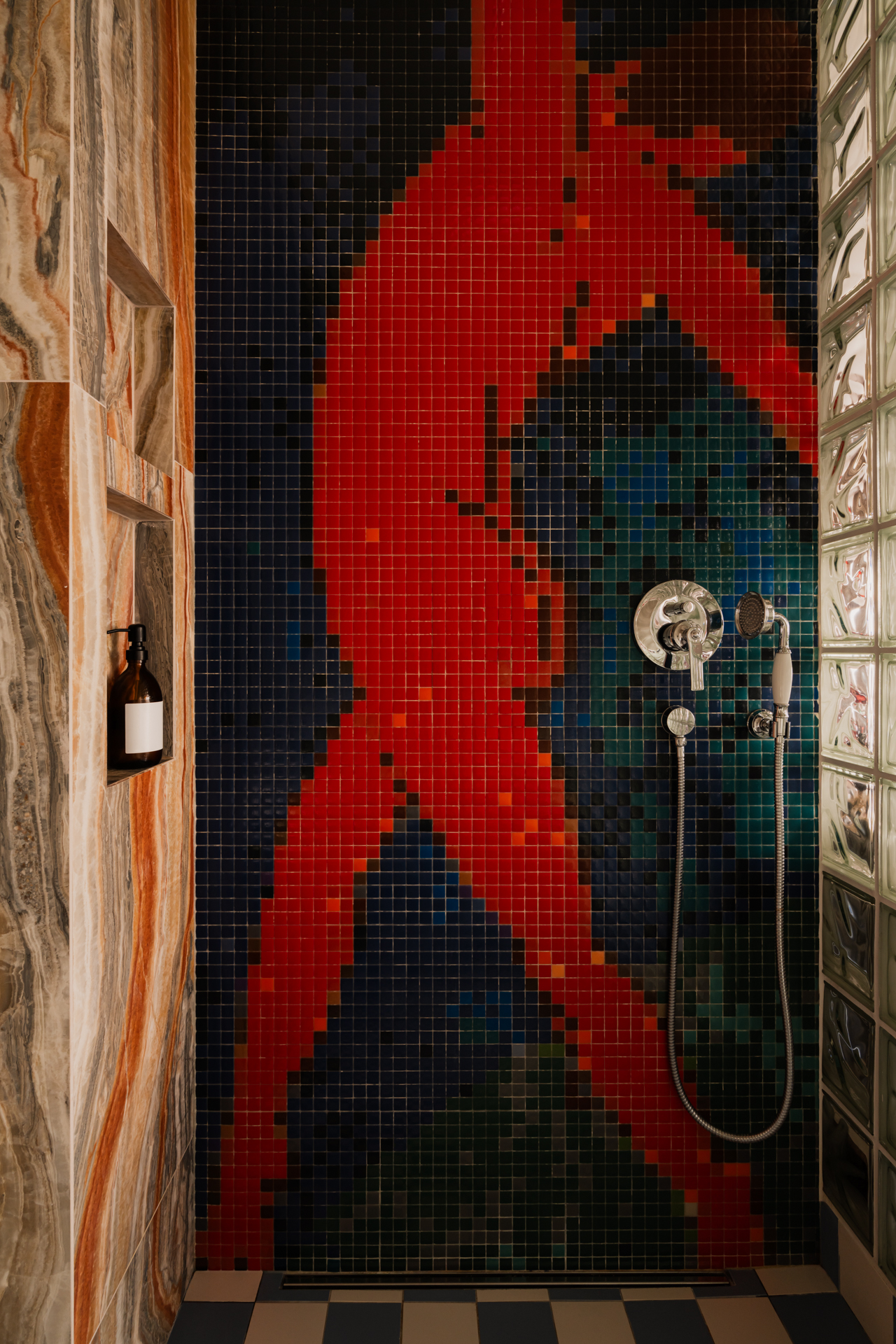 An image of a shower wall featuring a mosaic of a dancing form in red.