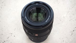 A Sony 50mm f/1.4 GM lens standing on a table with the optical elements showing.