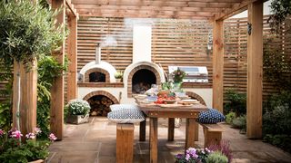 Outdoor kitchen ideas with timber pergola and pizza oven