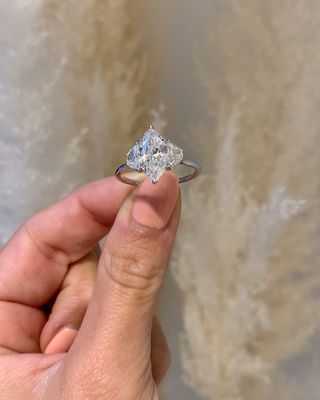 Woman holds up marquise cut diamond engagement ring.