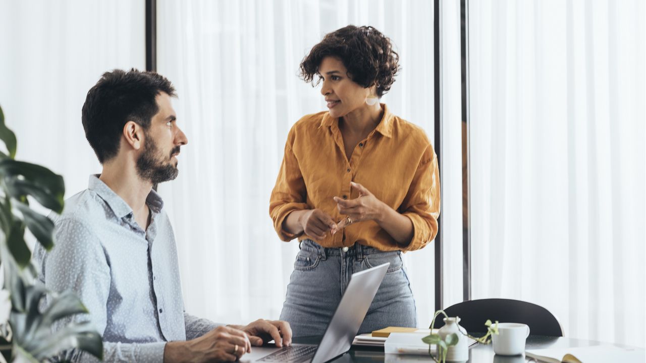 Two coworkers talk in the office.