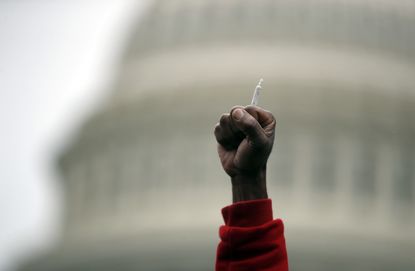 A man holds up a joint during a rally to support pot legalization.