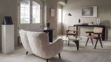 living room with limewash walls, boucle armchair, rattan chairs and contemporary lamp