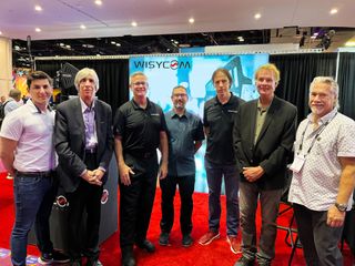 Smiling people from Wisycom and John B. Anthony Company stand together at InfoComm after announcing partnership.