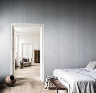 grey bedroom with textured wall covering, view through to living space, wooden floors