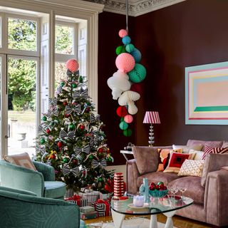 A bow-decorated Christmas tree next to a pink sofa