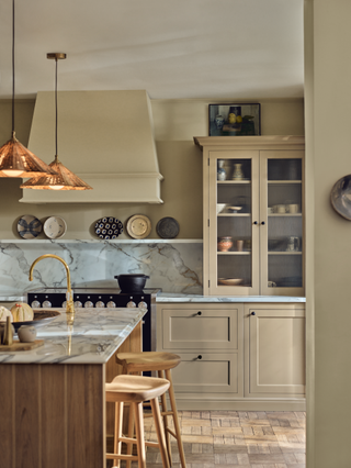 A kitchen with beige cabinetry with glass-fronts and a marble counter splash with plates on a shelf