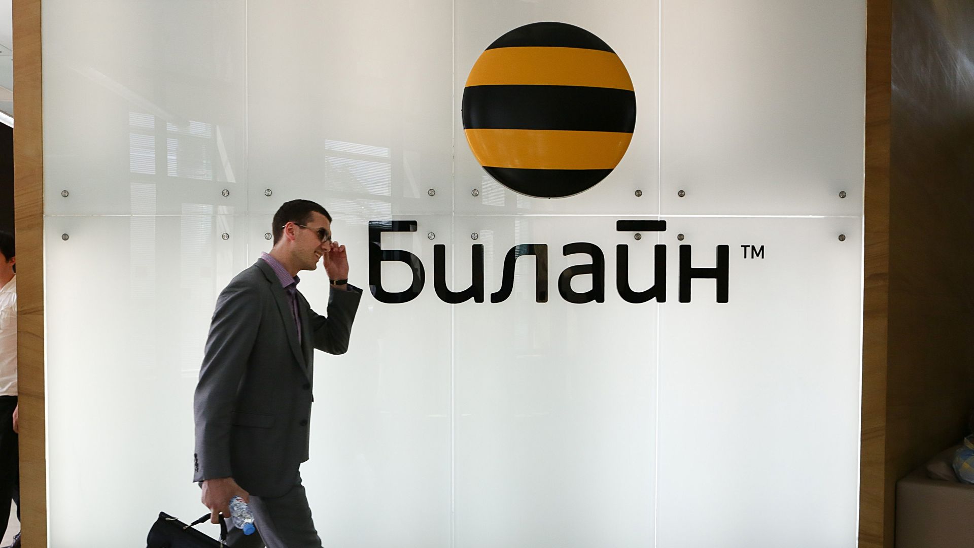 Visitors pass an illuminated logo in the foyer of the headquarters of Beeline, a division of Vimpelcom Ltd., in Moscow, Russia, on May 2013.