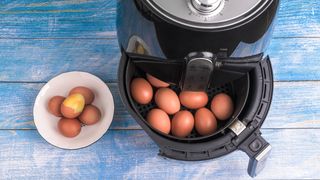 Whole eggs in an air fryer basket on a blue wooden table
