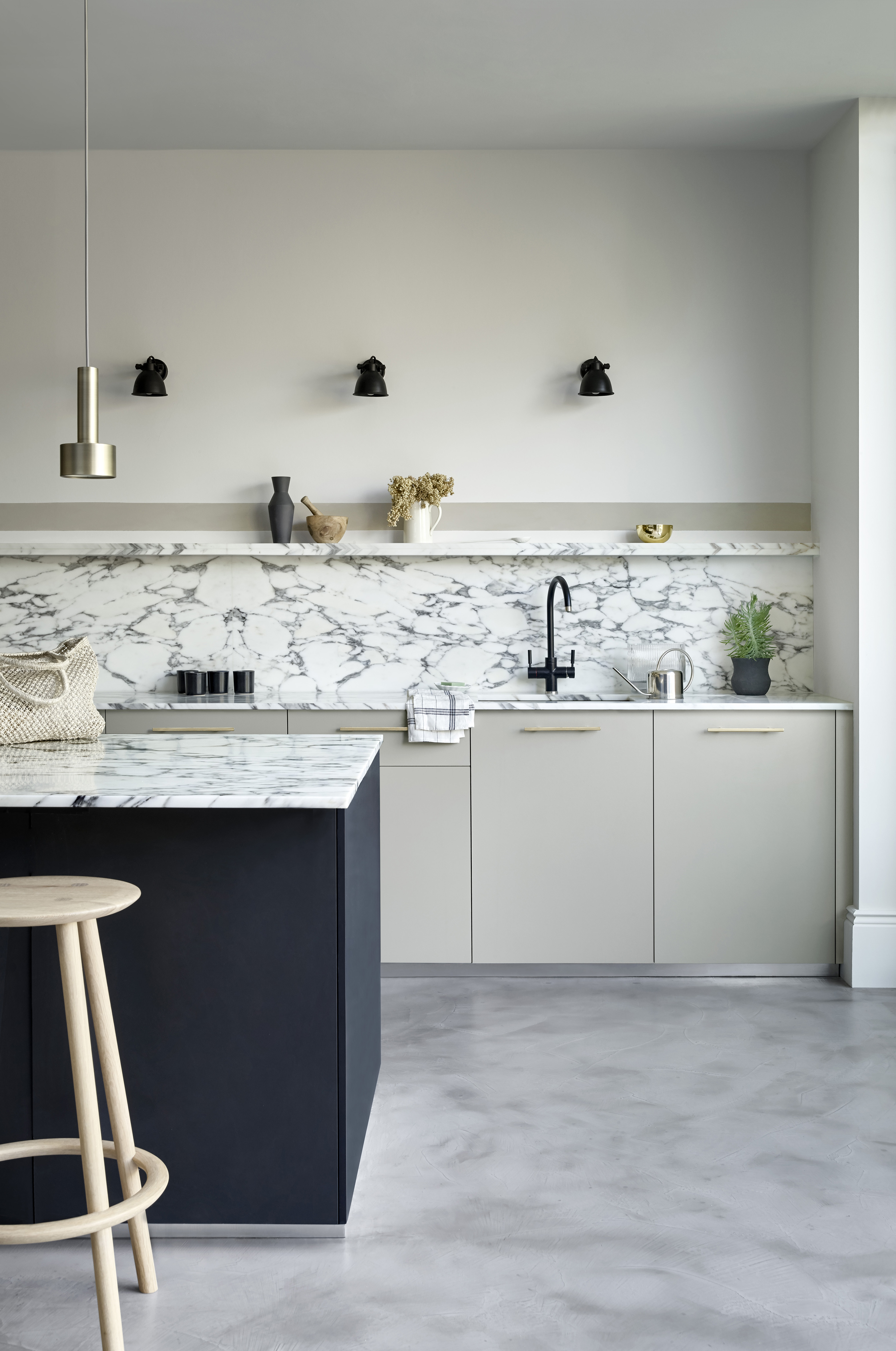 White marble kitchen worksurface and backsplash in a white scheme with midnight blue painted kitchen island.