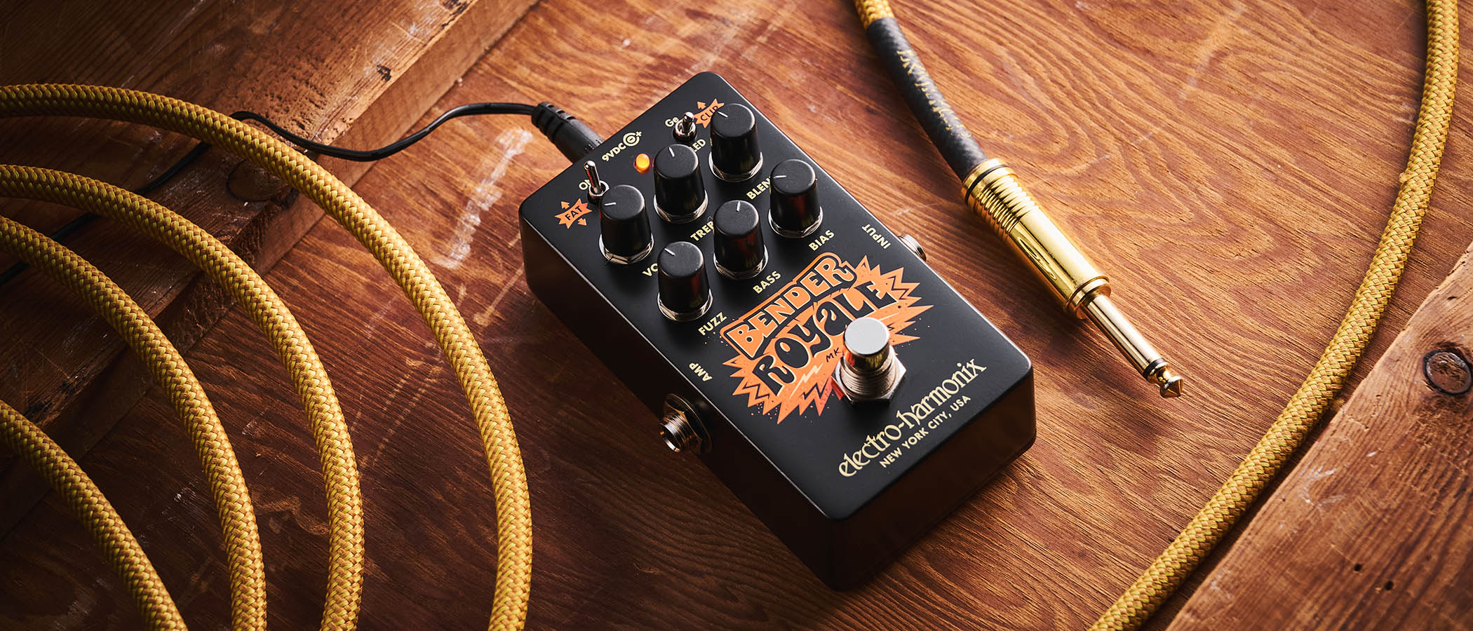Electro-Harmonix Bender Royale – the feature-packed fuzz pedal is finished in a black enclosure with orange graphics/text, and is photographed here in warm tones against a wooden background.