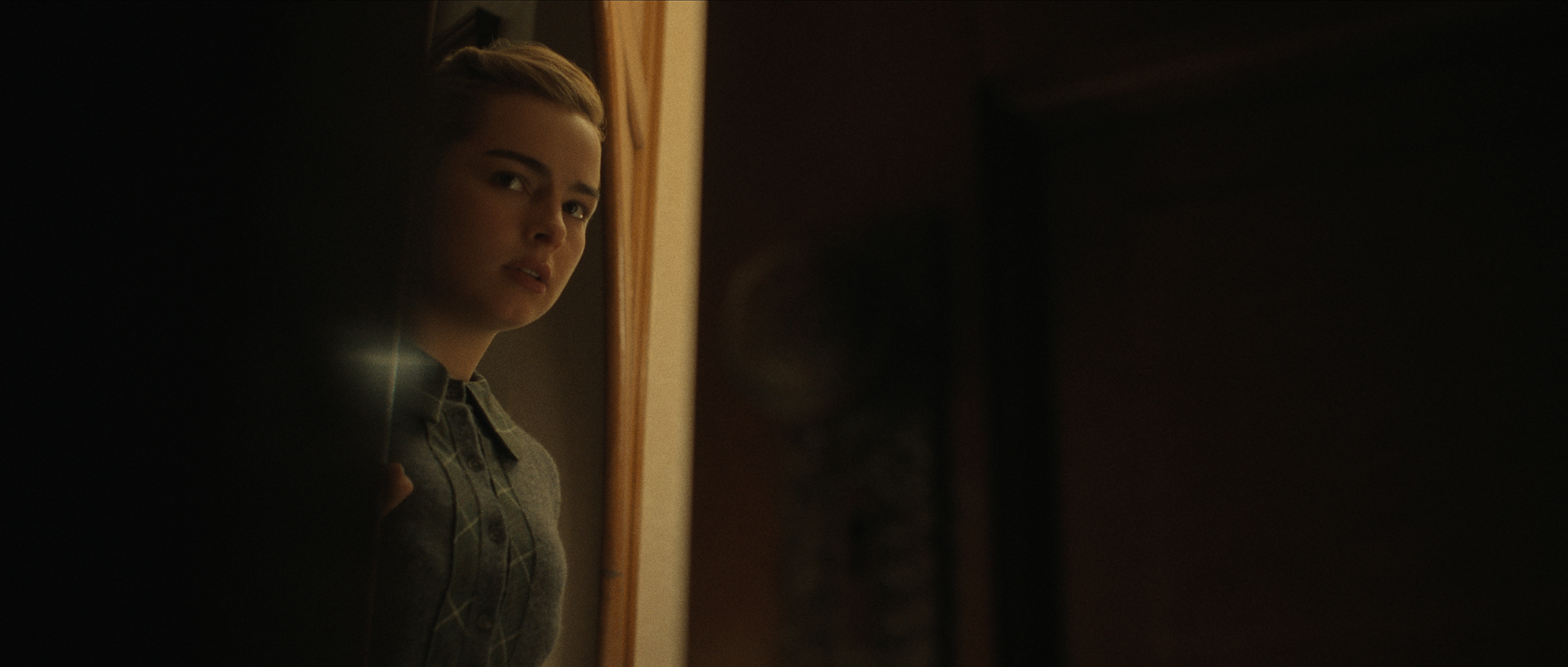 addison rae as Evelyn peering around a dark corner in monster the ed gein story