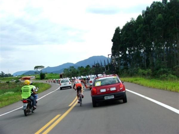 A rider grabs a bottle from his team car