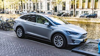 Tesla sedans in front of a Tesla sign