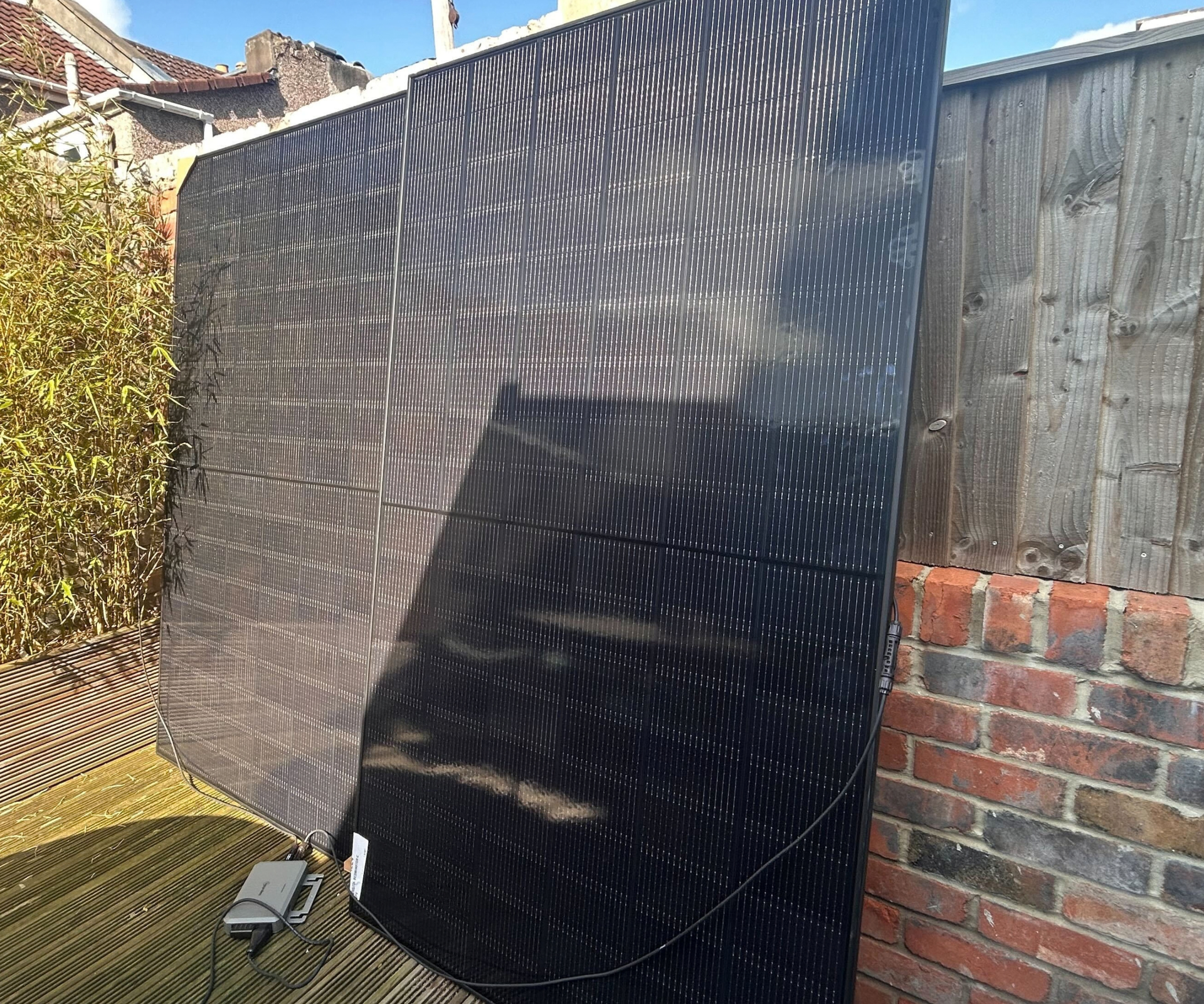 plug in solar panels leaned against brick wall and fence