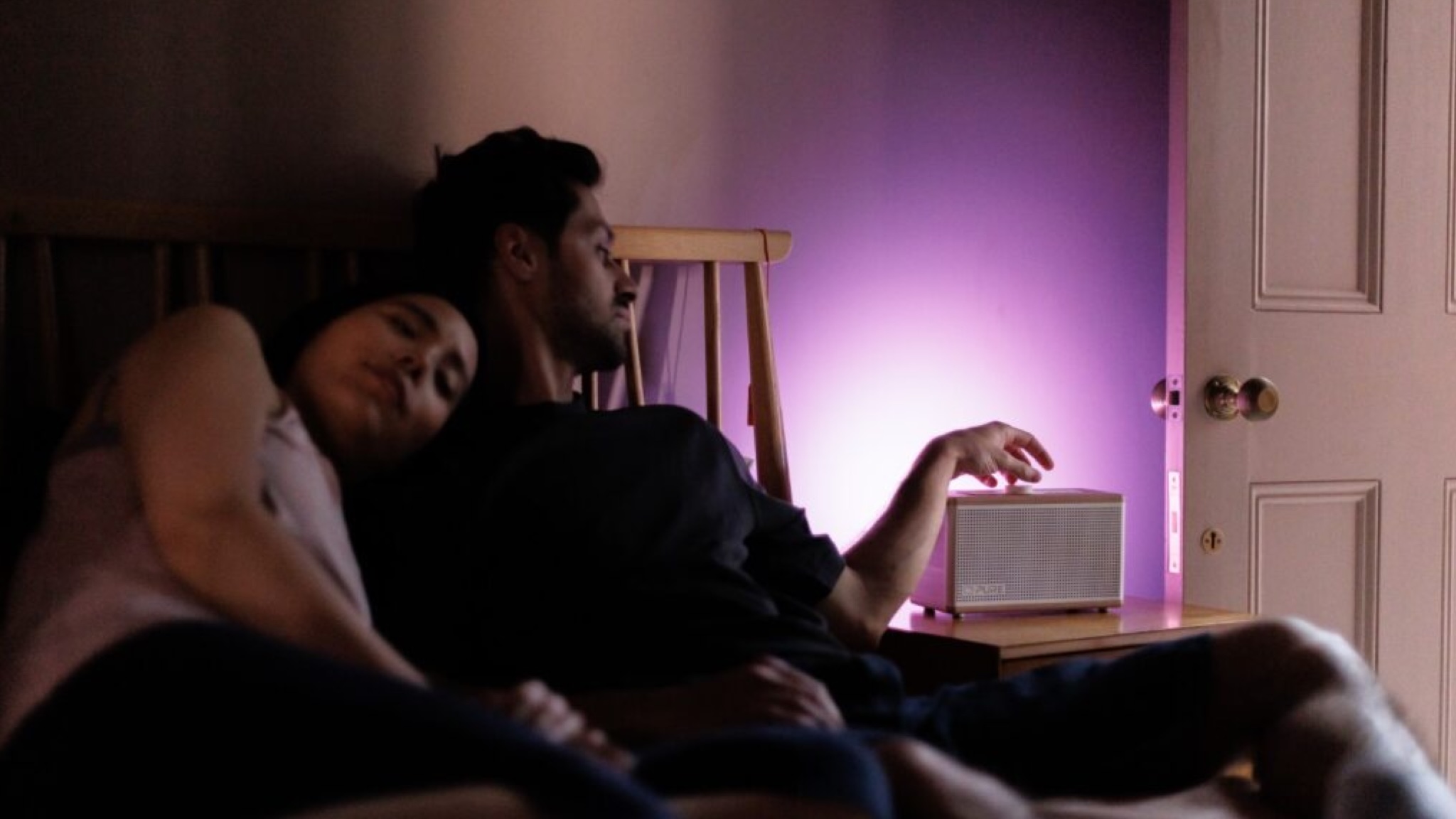 A couple snuggle on their bed while the Pure Classic Aura provides nice ambient lighting