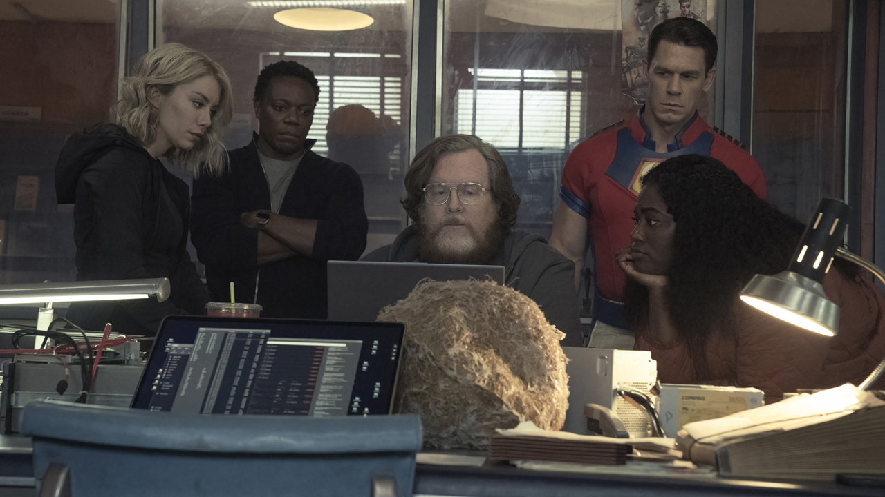 A screenshot of some of the Peacemaker cast sat around a computer in an office