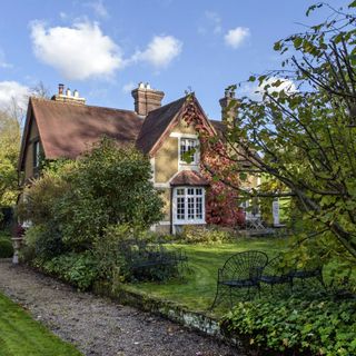 : Exterior of a Victorian cottage, converted outbuildings with lawn and gravel path in the foreground