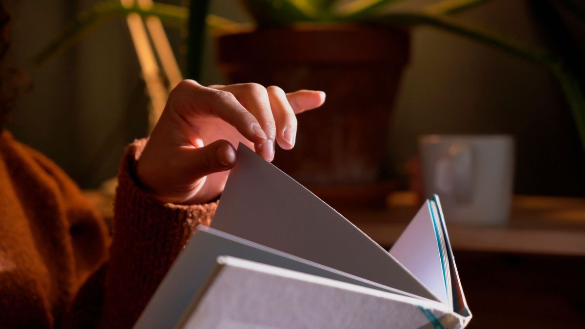 close up on a person&#039;s hand turning the page of a large book