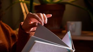 close up on a person's hand turning the page of a large book