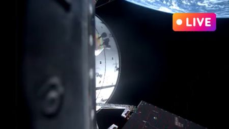 orion capsule in space with earth in the background there is a live text in top right corner to convey the live blog nature of the article.