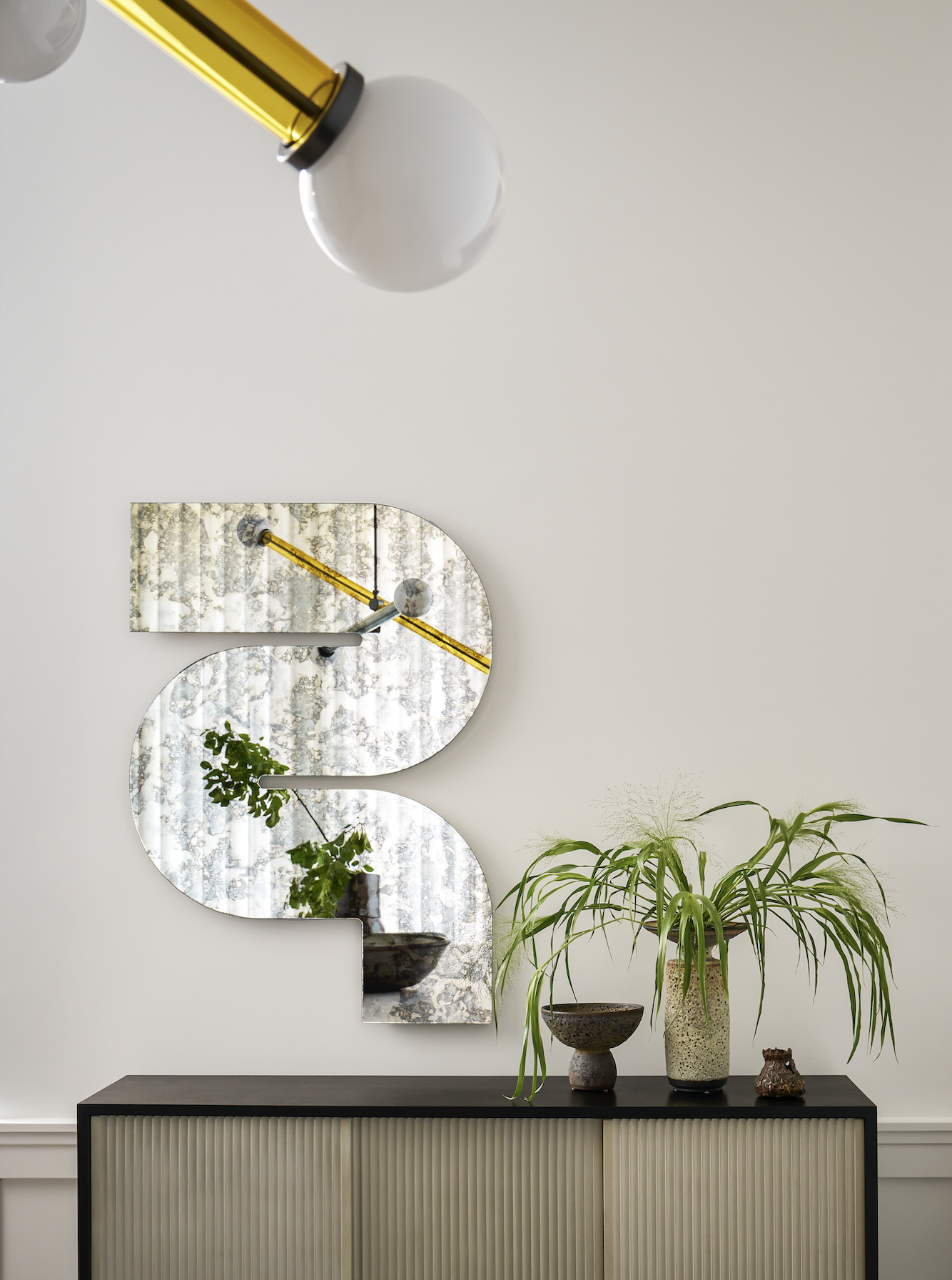 A corner in the hallway with an overhead light,and a mirror opposite it