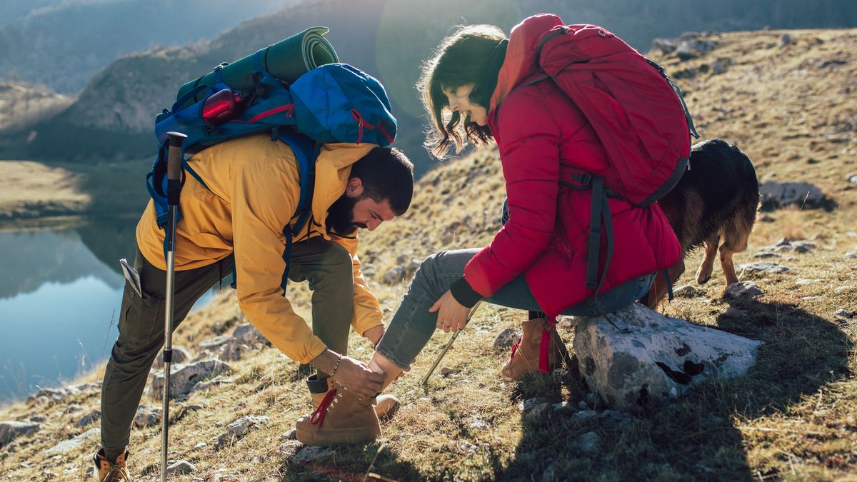 A man attends to a woman who has hurt her ankle on a hike