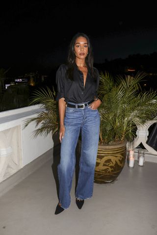Laura Harrier styles jeans and a black satin shirt.